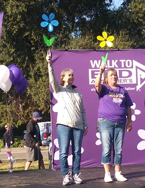 Laura McDermott raises a blue flower at Walk to End Alzheimer's