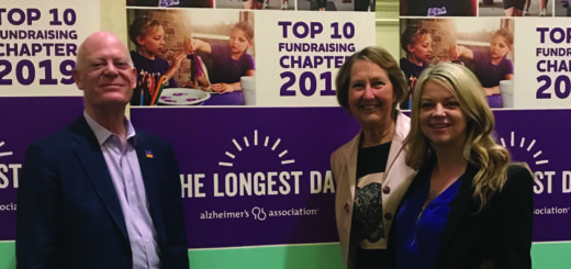 Kirsten Guanella poses with Bart and Nancy under The Longest Day Top 10 Banner
