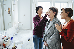 Daughters in the bathroom caring for their mother who has Alzheimer's 