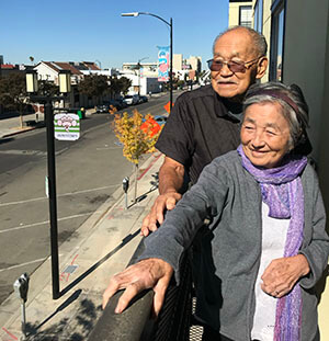 Eiko and James who both have dementia, stand on the balcony of their apartment in Japantown