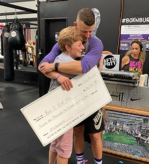 Kevan holds Alzheimer's donation check while hugging mom who is living with Alzheimer's