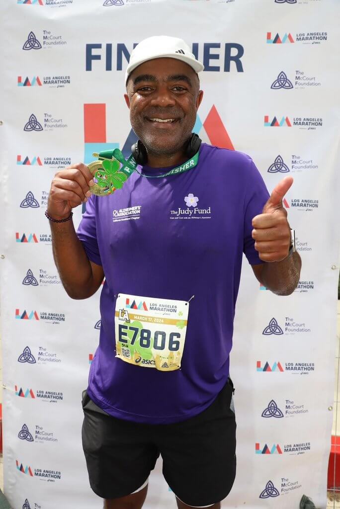 A man celebrates running the NY City Marathon in an Alzheimer's Association tshirt