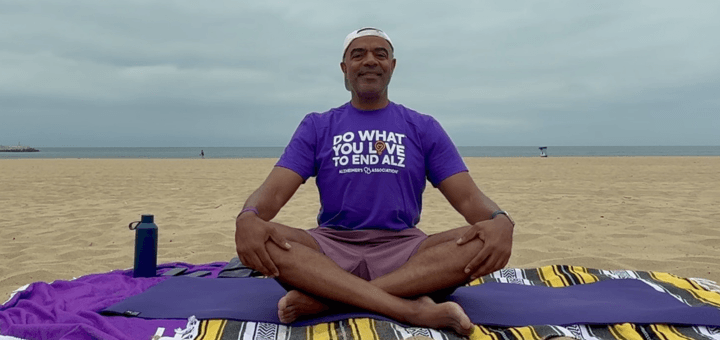 A man performing yoga on the beach wearing a Do What You Love tshirt